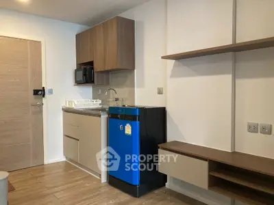 Modern compact kitchen with blue fridge and wooden cabinets in cozy apartment