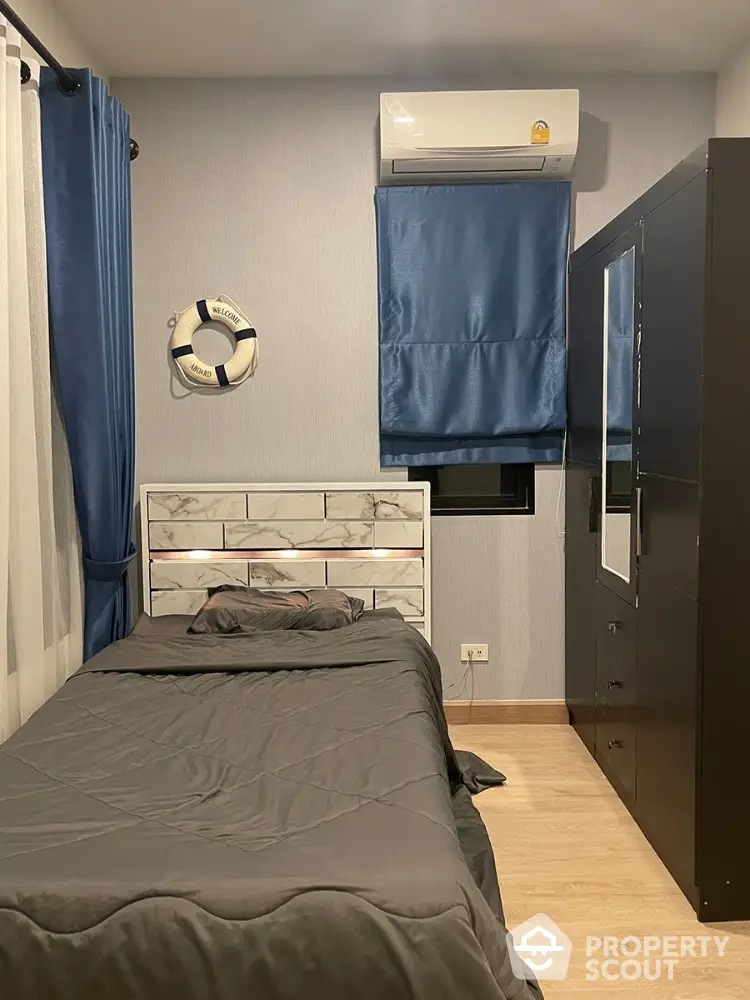 Cozy bedroom with modern design, featuring a comfortable bed, sleek furniture, and air conditioning, perfect for restful nights in a compact urban apartment.