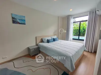 Cozy bedroom with large window and modern decor in a serene setting.