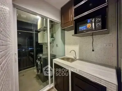 Modern kitchen with sleek cabinetry and built-in appliances, featuring a washing machine and microwave.