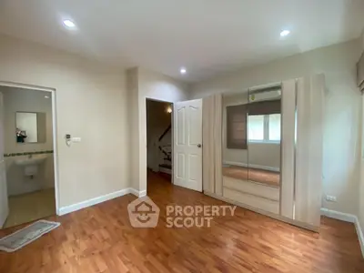 Spacious bedroom with wooden flooring and mirrored wardrobe