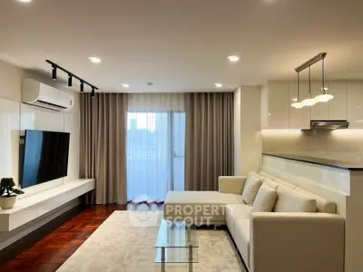 Modern living room with sleek design, featuring a cozy sectional sofa, wall-mounted TV, and elegant lighting.