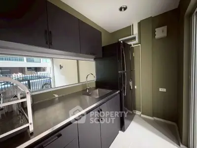 Modern kitchen with sleek black cabinets and stainless steel appliances.