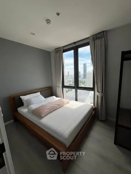 Modern bedroom with city view and large window, featuring a cozy bed and elegant curtains.