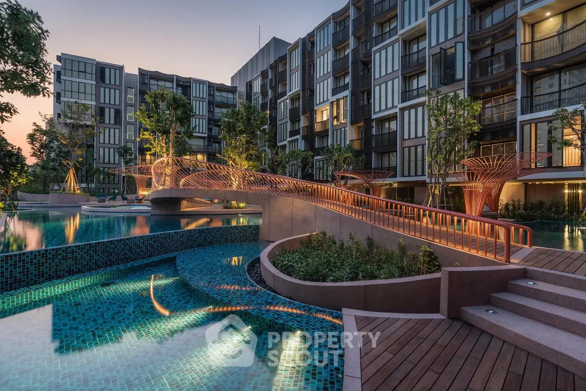 Luxurious modern apartment complex with stunning pool and landscaped gardens at sunset.