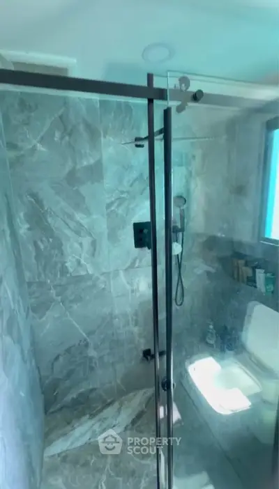 Modern bathroom with glass shower enclosure and marble tiles