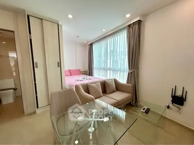 Modern studio apartment with glass dining table and cozy seating area