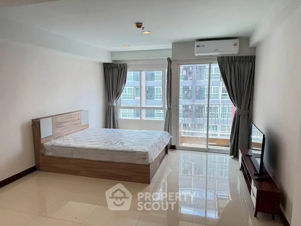Spacious bedroom with large windows and modern furnishings in a high-rise apartment.