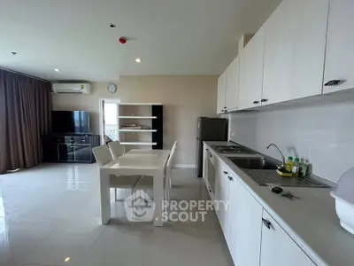 Spacious modern kitchen and dining area with sleek white cabinetry and open layout.