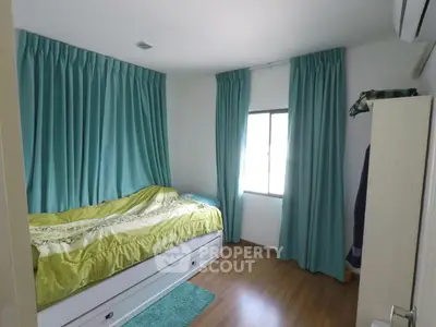 Cozy bedroom with teal curtains and wooden flooring