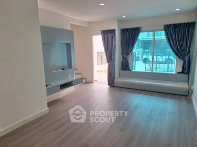 Spacious living room with large window and modern flooring, perfect for natural light lovers.