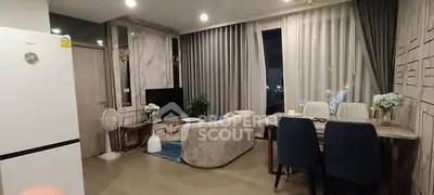 Modern living room with elegant decor and dining area, featuring large windows and stylish furniture.