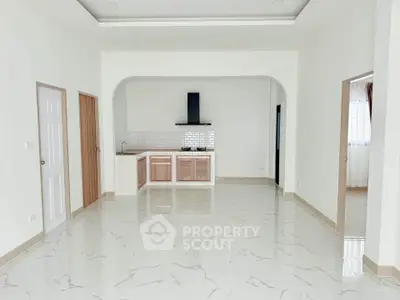 Spacious open-plan kitchen with modern design and marble flooring, featuring a sleek gas stove and ample natural light.