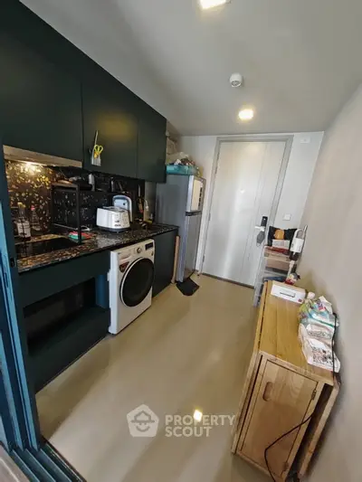 Modern compact kitchen with washing machine and sleek cabinetry in urban apartment