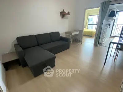Modern living room with sleek furniture and open layout leading to a bright bedroom with city view.