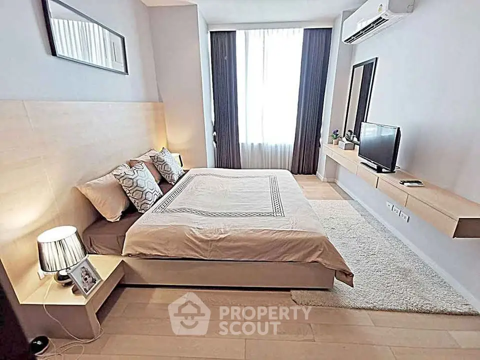 Modern bedroom with stylish decor, featuring a cozy bed, wall-mounted TV, and elegant lighting.