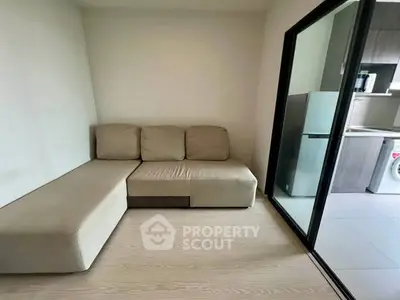 Cozy living room with modern sofa and sliding glass door to kitchen area.
