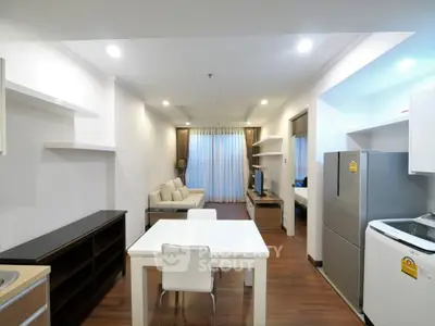 Modern open-plan living room with kitchen and dining area, featuring sleek furniture and bright lighting.