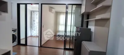 Modern apartment interior with sliding glass doors, featuring bedroom and laundry area.