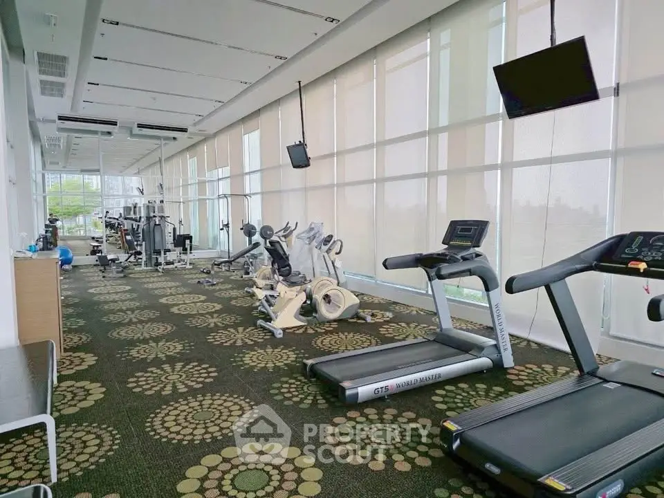 Spacious modern gym with state-of-the-art equipment and large windows for natural light.