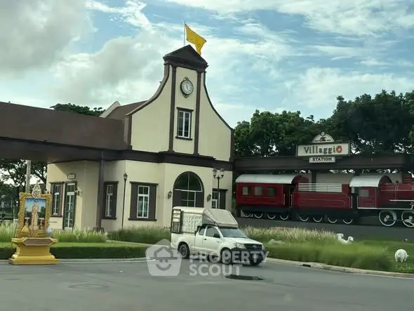 Charming train station facade with vintage clock and red train display.