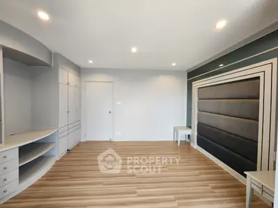 Spacious modern living room with elegant wood flooring and built-in storage solutions.