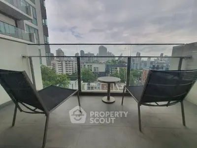Modern balcony with city view, featuring sleek chairs and glass railing.