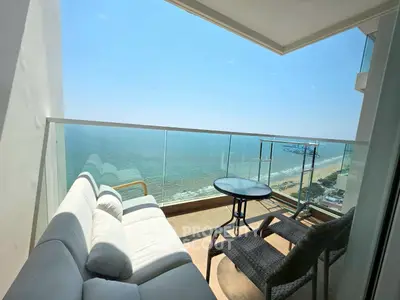 Stunning beachfront balcony with panoramic ocean views and cozy seating area.