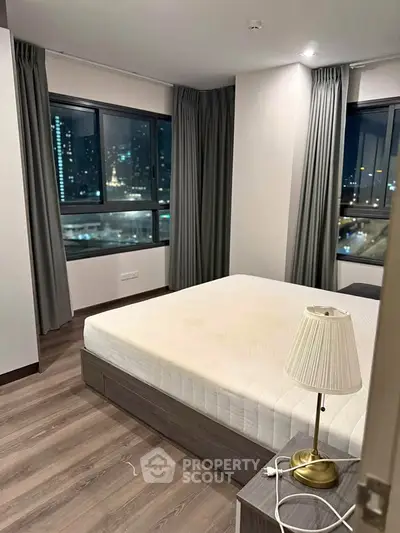 Modern bedroom with city view, featuring large windows and elegant decor.