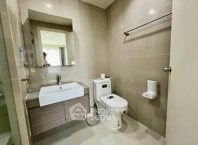 Modern bathroom with sleek fixtures and neutral tones, featuring a stylish sink and toilet.