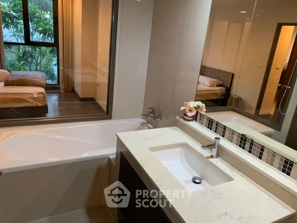 Modern bathroom with bathtub and view into cozy bedroom, perfect for relaxation.