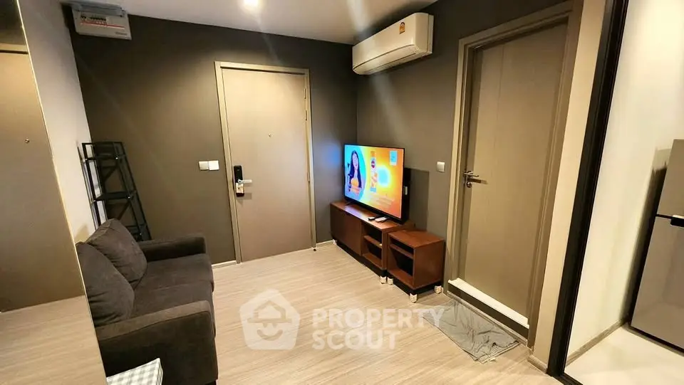 Modern living room with sleek design, featuring a cozy sofa, flat-screen TV, and air conditioning.