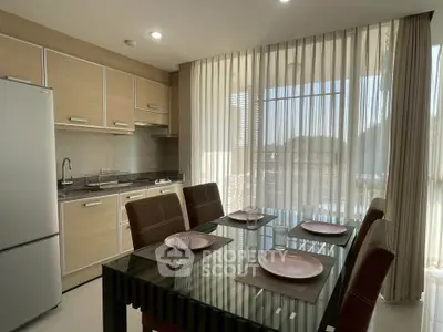 Modern kitchen with dining area featuring sleek cabinetry and large windows for natural light.