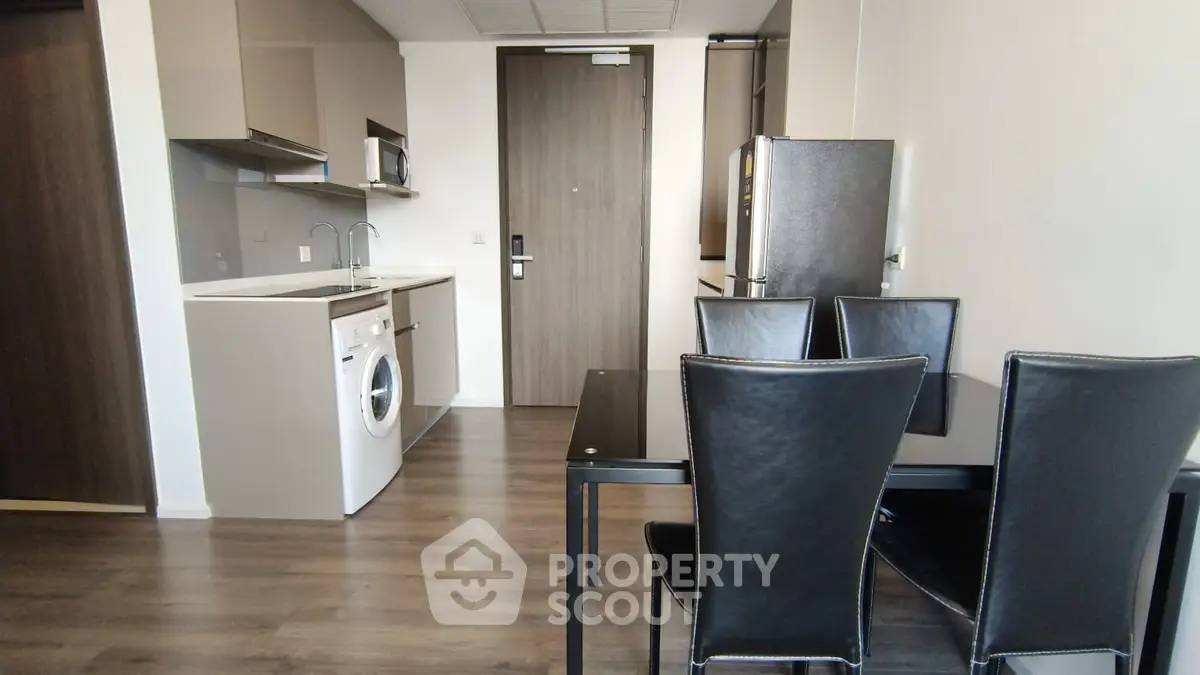 Modern apartment interior with kitchen and dining area featuring sleek appliances and stylish furniture.