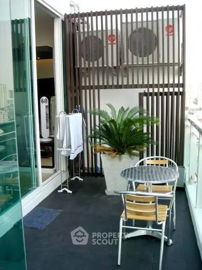 Chic balcony with modern seating and lush plant, perfect for urban relaxation.