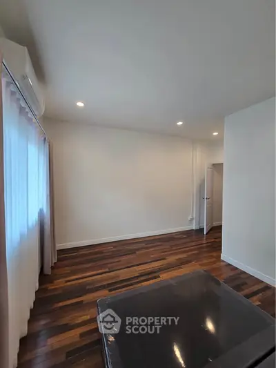 Spacious room with wooden flooring and natural light, ideal for versatile living space.