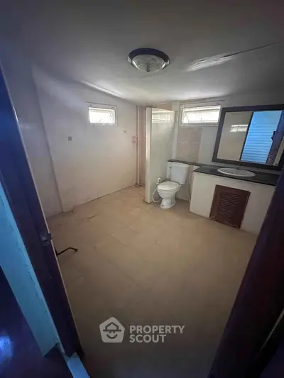 Spacious bathroom with modern fixtures and natural light from small windows.