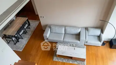 Spacious modern living room with elegant furniture and dining area, featuring hardwood floors and stylish decor.