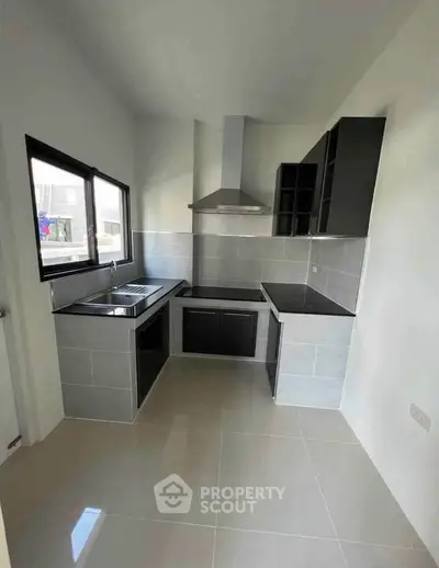 Modern kitchen with sleek black cabinetry and stainless steel appliances in a compact layout.