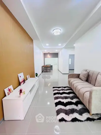 Modern living room with stylish decor and open kitchen layout, featuring sleek furniture and elegant lighting.