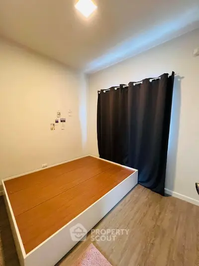 Spacious bedroom with modern flooring and large window with blackout curtains.
