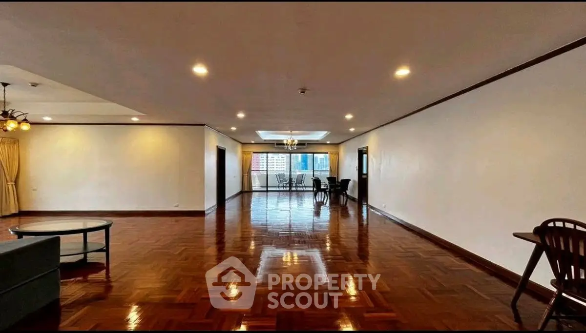 Spacious living room with polished wooden floors and city view balcony.