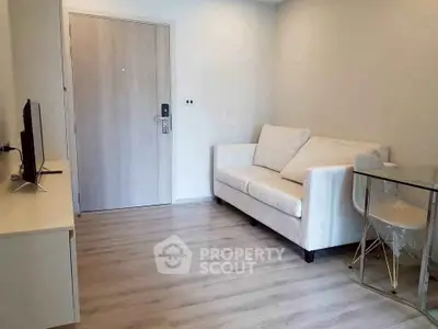 Modern living room with sleek sofa and TV, featuring minimalist design and light wood flooring.