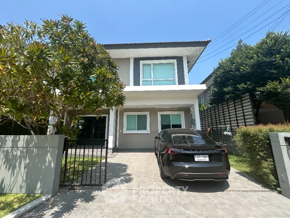 Charming two-story home with lush landscaping and modern design, featuring a spacious driveway and a welcoming entrance.