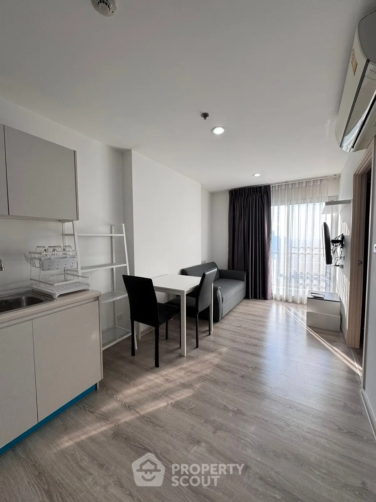 Modern living room with open kitchen, sleek furniture, and natural light in a stylish apartment.