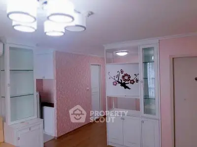 Charming interior with pastel pink walls, elegant white cabinetry, and modern lighting fixtures, perfect for a cozy living space.