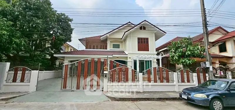 Charming two-story house with gated entrance and lush greenery in a serene neighborhood.