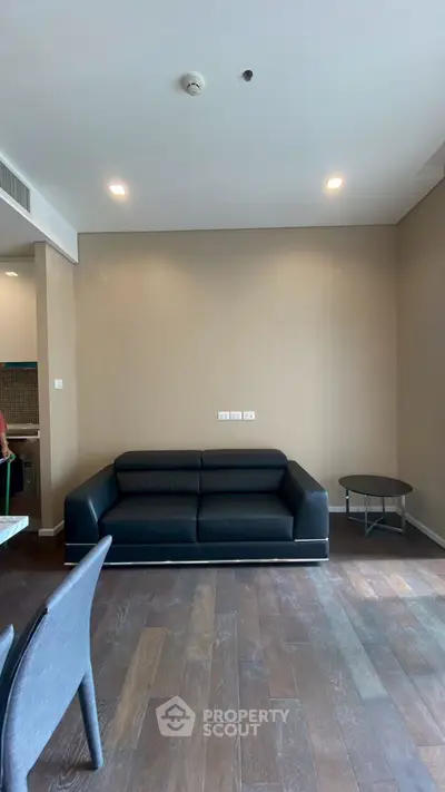 Modern living room with sleek black sofa and wooden flooring