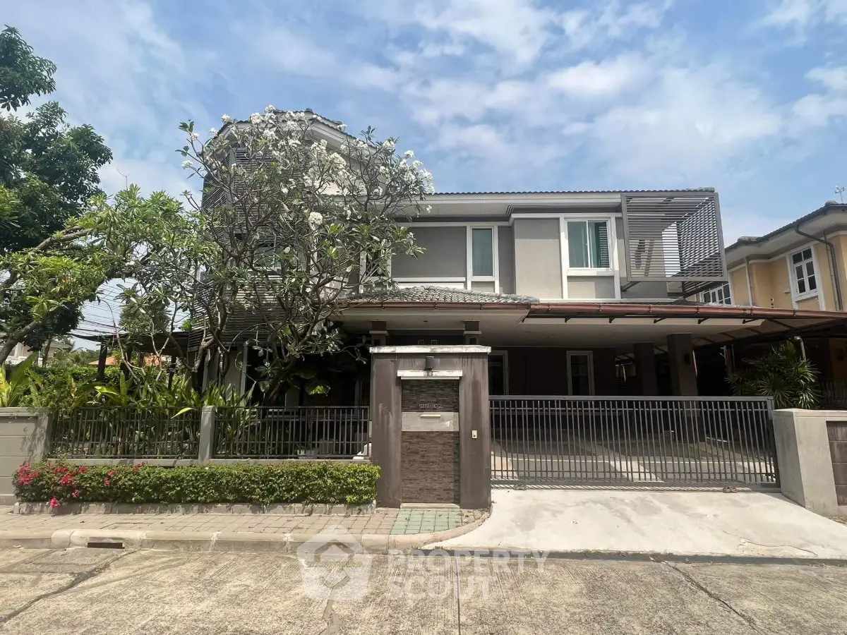Modern two-story house with spacious driveway and lush greenery in a serene neighborhood.