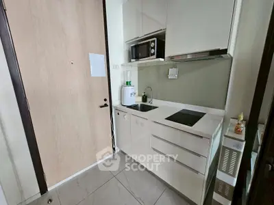 Modern compact kitchen with sleek white cabinets and built-in appliances.
